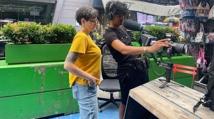 Two crew members setting up a gimbal-mounted camera with a shotgun mic in Times Square.